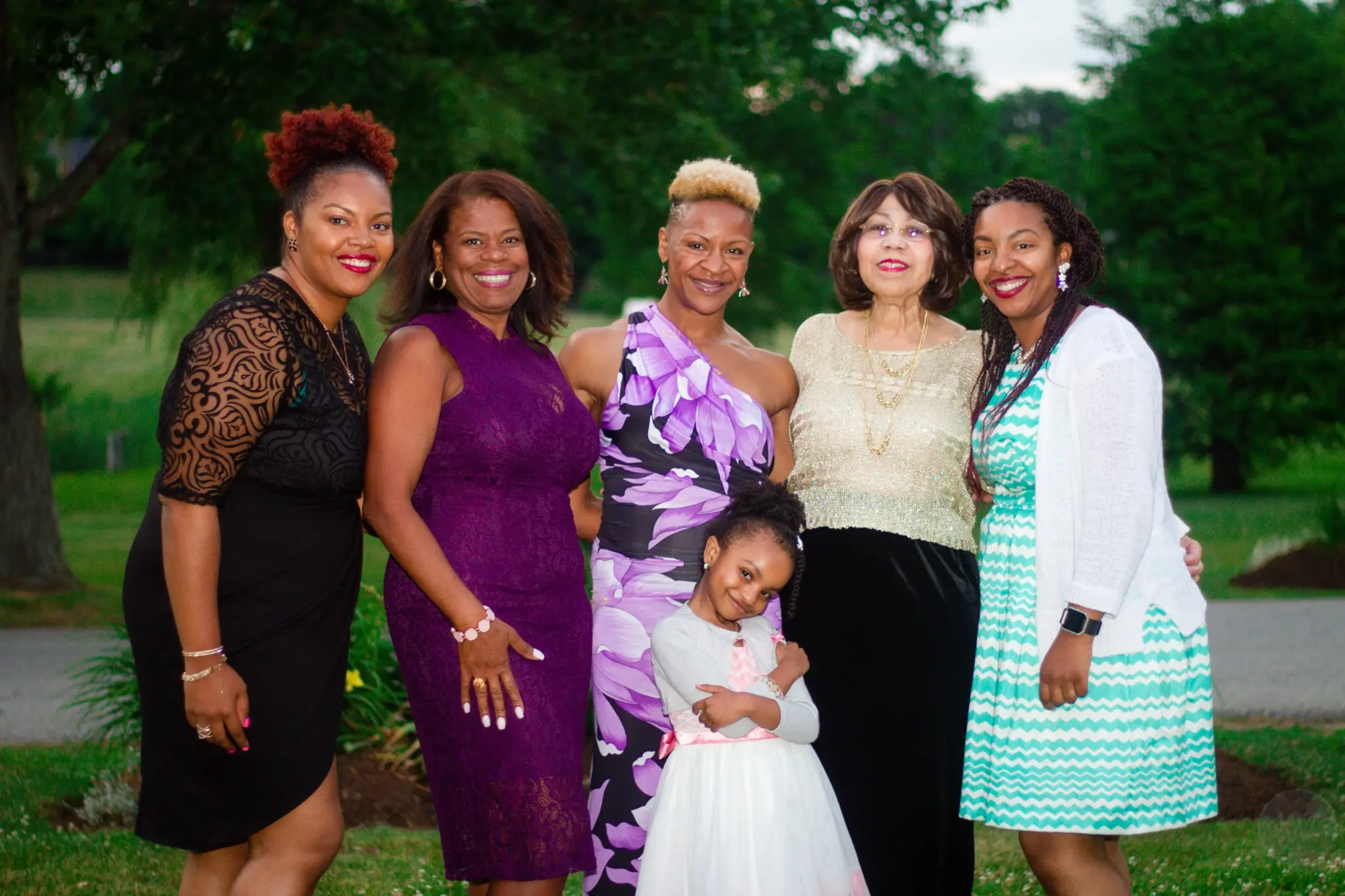 Five wedding guests and a flower girl posing outdoors