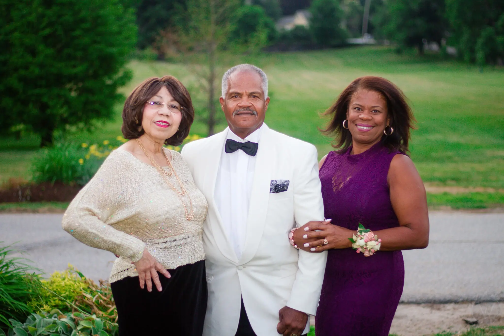 Three wedding guests posing together outdoors