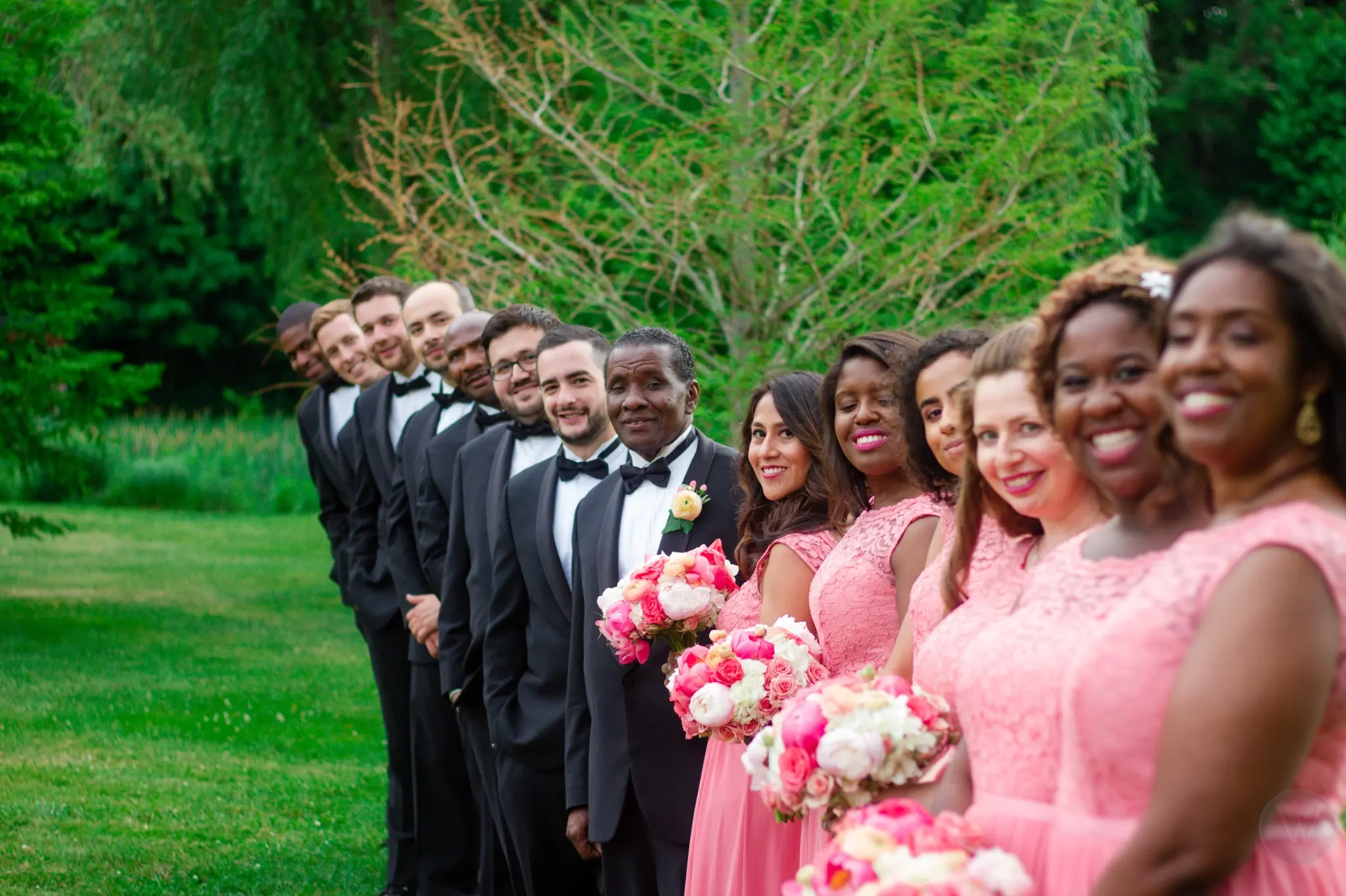 Wedding party lined up outdoors with pink bouquets