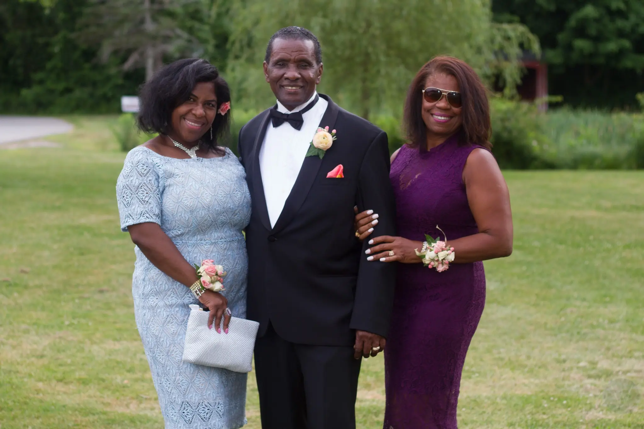 Groom posing outdoors with two wedding guests